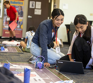 1.	Coding coach (and high school student leader) supporting a middle school student through a coding mat challenge.