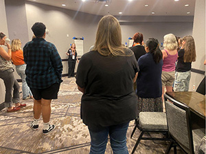 Participants gather around a de-fronted classroom for the mini-lesson.