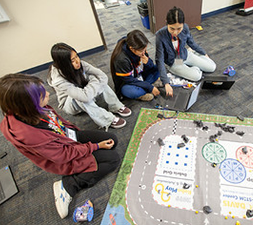 2.	Coding coach (and high school student leader) and a high school team working on their final coding project, programming their robot to explore the asteroid belt to collect samples.
